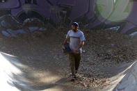 Skateboarder Dallas Oberholzer, 46, walks with his skateboard at at the Germiston Lake Skateboard Park, near Johannesburg, Saturday, July 3, 2021. The age-range of competitors in skateboarding's Olympic debut at the Tokyo Games is remarkably broad and Oberholzer will go wheel-to-wheel with skaters less than half his age. (AP Photo/Denis Farrell)