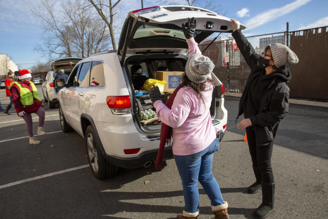Volunteers load food into vehicles at the Meadowlands YMCA in East Rutherford, N.J., Tuesday, Dec. 15, 2020. The organization says it is giving away 200,000 meals per month to people with food insecurity at this location, more than doubled since the summer. (AP Photo/Ted Shaffrey)