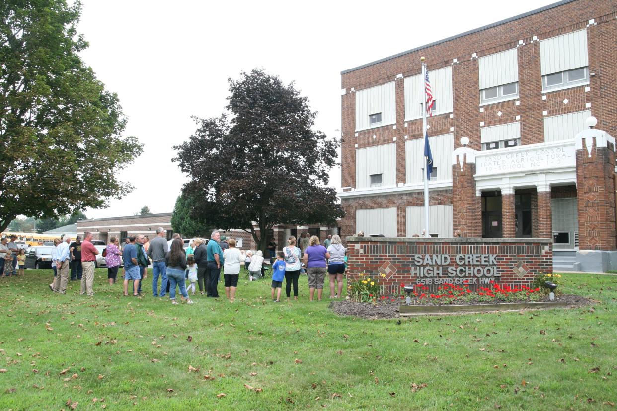 Sand Creek school alumni, staff, retirees and community members gathered Aug. 16, 2021, for a program that marked the 100th anniversary of the groundbreaking for what is now Sand Creek Jr./Sr. High School. Sand Creek voters are being asked to approve a $15.1 million bond proposal to pay for building and traffic projects.