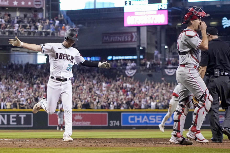 Arizona Diamondbacks' Pavin Smith celebrates after scoring the game winning run past Philadelphia Phillies catcher J.T. Realmuto on a single by Ketel Marte during the ninth inning in Game 3 of the baseball NL Championship Series in Phoenix, Thursday, Oct. 19, 2023. (AP Photo/Brynn Anderson)