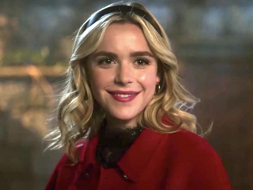 Kiernan Shipka wearing a balck headband and red coat as Sabrina Spellman on "Riverdale."