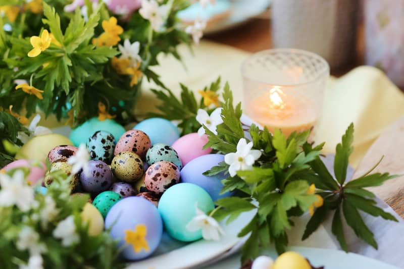 A beautiful spring Easter picture with spring flowers, a candle and colorful chicken and quail eggs