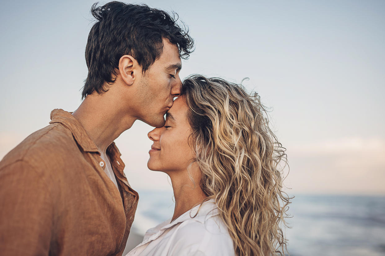 Man and woman, happy young couple standing on the beach by the sea. Man is kissing a woman. sex