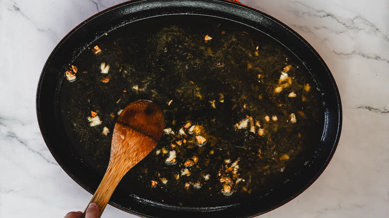 Wooden spoon stirring sauce in pan