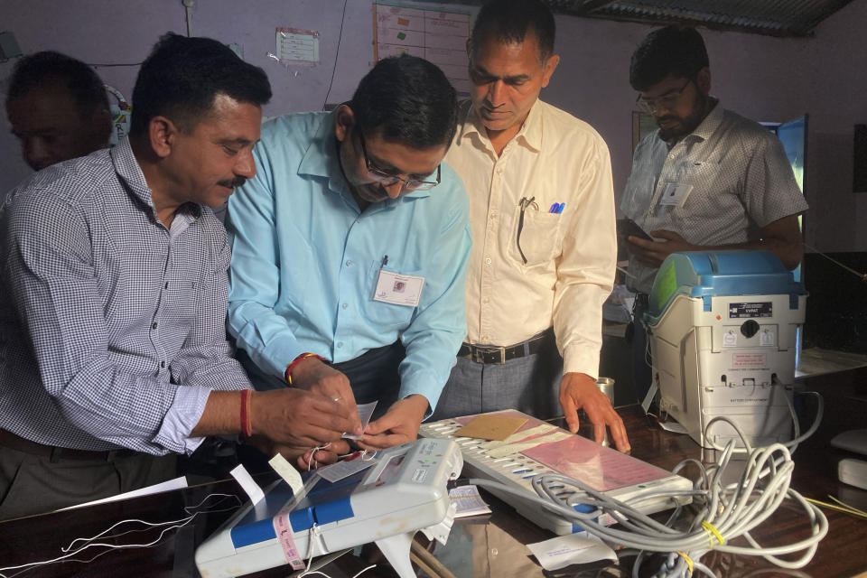 Funcionarios electorales revisan y sellan una máquina de voto electrónico antes de permitir que los votantes emitan su sufragio en una casilla electoral, en la última ronda de la elección general, de 6 semanas de duración, cerca de Dharamshala, India, el sábado 1 de junio de 2024. (AP Foto/Ashwini Bhatia)