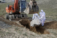 FILE - In this Friday, March 27, 2020 file photo, municipality workers bury the body of coronavirus victim on the outskirts of Herat province west of Kabul, Afghanistan. Some 200,000 Afghans and counting have returned from Iran to their home country after losing their jobs in the coronavirus pandemic or out of fear of getting infected. They are flowing across the border from a country that has one of the world's worst outbreak to an impoverished nation that is woefully unprepared to deal with the virus. (AP Photo/Hamed Sarfarazi, File)