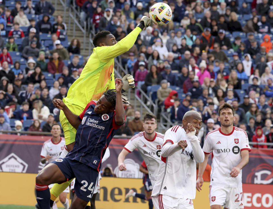 Toronto FC goalkeeper Sean Johnson punches the ball over New England Revolution defender Nick Lima (24) while defending the net in the second half of an MLS soccer match, Sunday, March 3, 2024, in Foxborough, Mass. (AP Photo/Mark Stockwell)