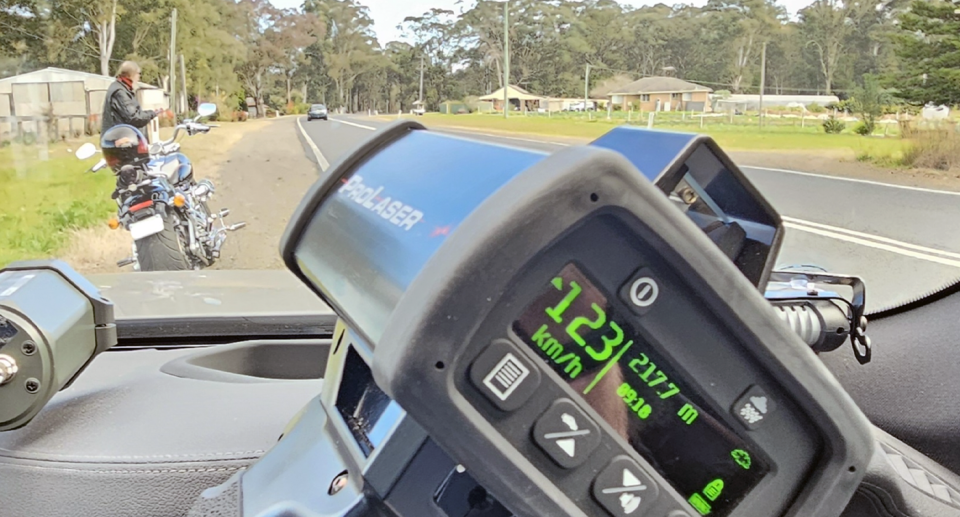 A NSW man and his motorbike, after having been pulled over in Agnes Banks driving double the legal speed limit. A police radar speed gun is also seen. 
