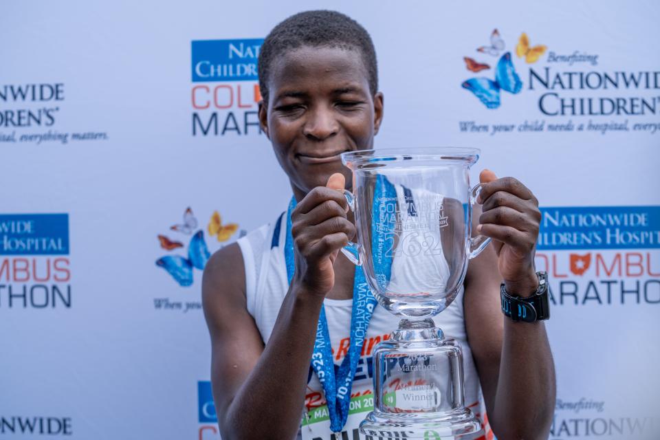 Damaris Areba holds the winning trophy for coming first of the women with a time of 3:24:38 in the Nationwide Children’s Hospital Columbus Marathon.