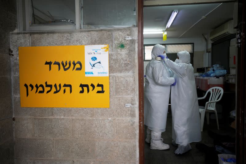 Employees of Chevra Kadisha, the main group that oversees Jewish burials in Israel, adjust their protective gear at a special centre that prepares bodies of Jews who died from the coronavirus disease (COVID-19), at a cemetery in Tel Aviv