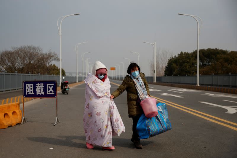 A leukaemia patient and her mother who arrived from Hubei province cross a checkpoint at the Jiujiang Yangtze River Bridge in Jiujiang