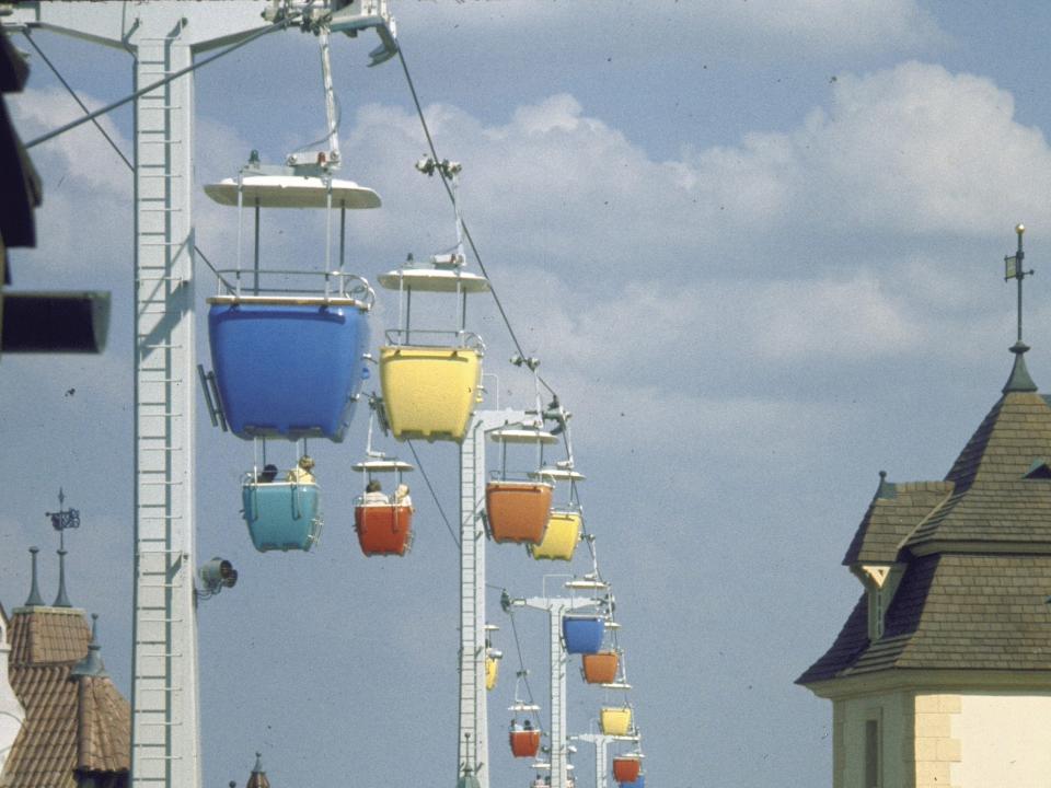 Pastel colored cable cars moving in the air along a cable line.