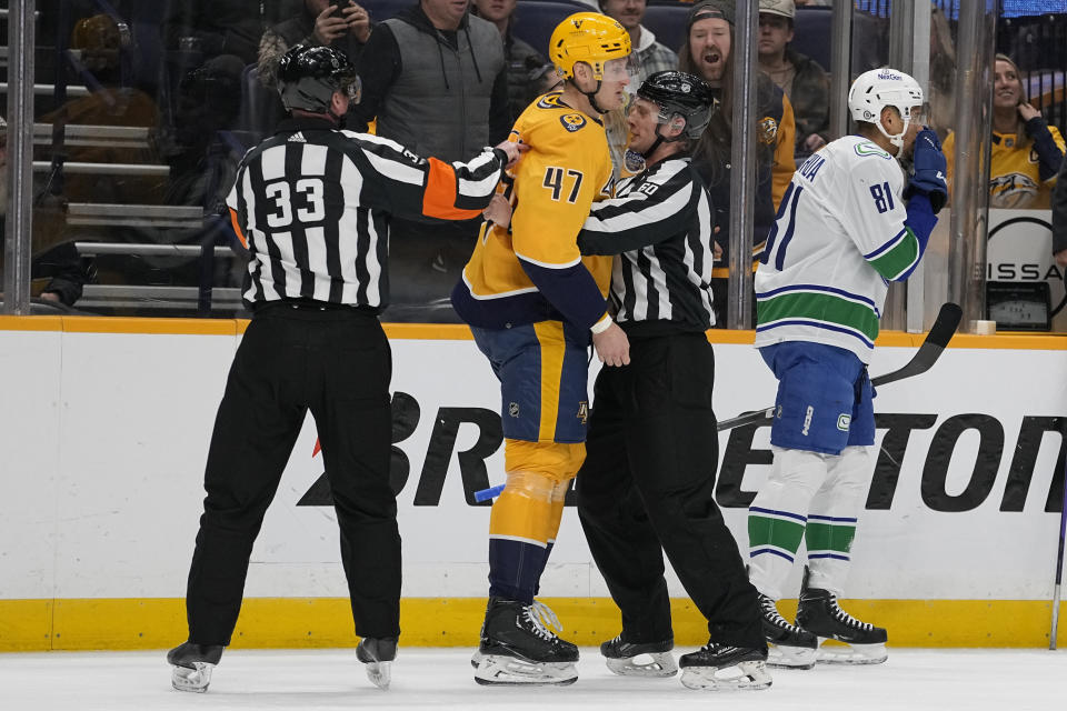 Nashville Predators right wing Michael McCarron (47) is restrained by referees has he is given a penalty unsportsmanlike behavior during the first period of an NHL hockey game against the Vancouver Canucks, Tuesday, Dec. 19, 2023, in Nashville, Tenn. (AP Photo/George Walker IV)