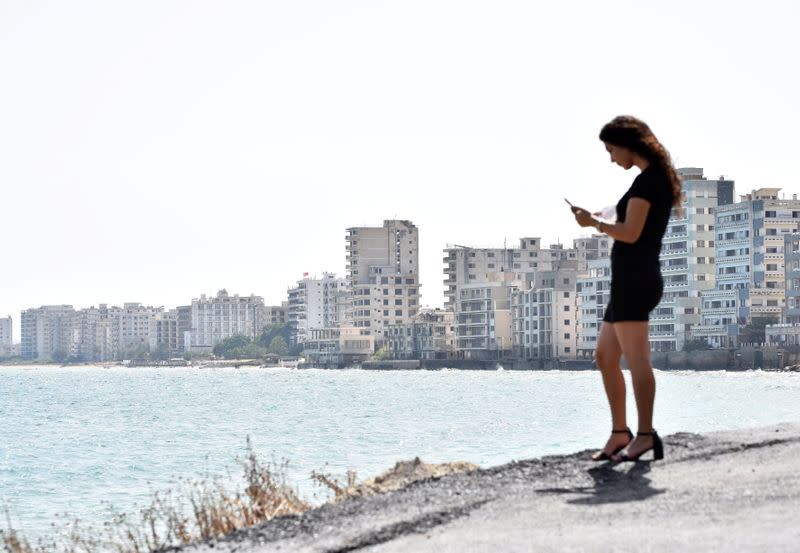 A woman looks at her mobile phone in the abandoned coastal area of Varosha