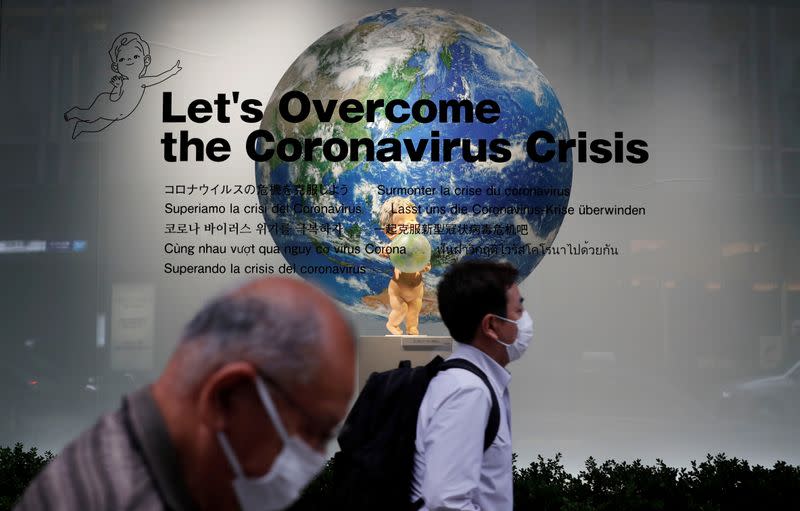 Pedestrians wearing protective face masks, following the coronavirus disease (COVID-19) outbreak, walk past a show window of a department store in Tokyo