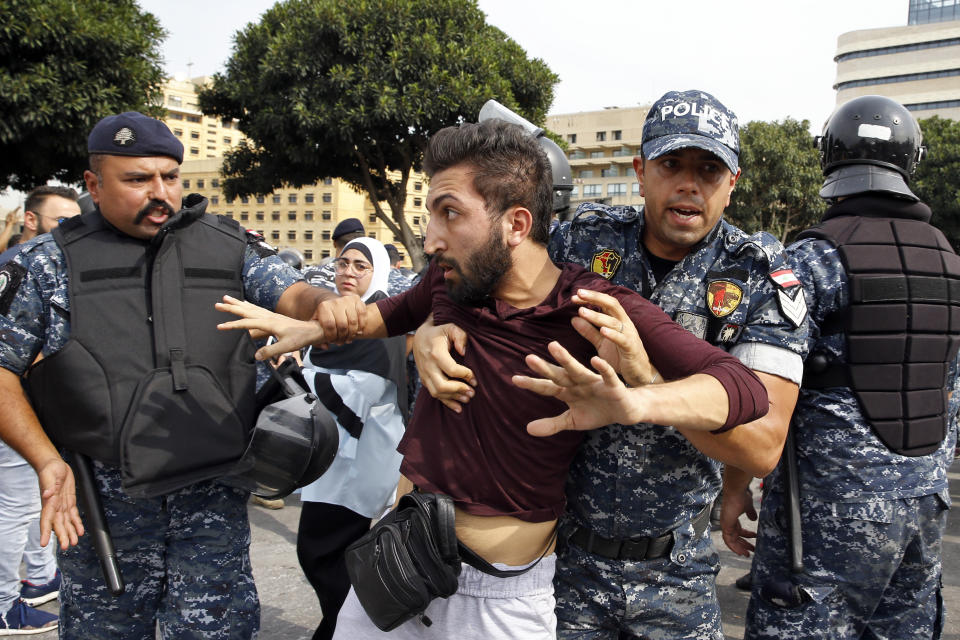 Riot police remove an anti-government protester blocking a main highway with his body in Beirut, Lebanon, Saturday, Oct. 26, 2019. The removal of the roadblocks on Saturday comes on the tenth day of protests in which protesters have called for civil disobedience until the government steps down. (AP Photo/Bilal Hussein)