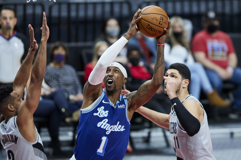 Los Angeles Lakers guard Kentavious Caldwell-Pope, center, shoots between Portland Trail Blazers guard CJ McCollum, left, and center Enes Kanter during the first half of an NBA basketball game in Portland, Ore., Friday, May 7, 2021. (AP Photo/Craig Mitchelldyer)