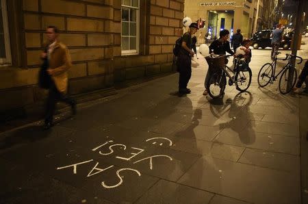 People pass some 'Yes' graffiti on the Royal Mile in Edinburgh, Scotland September 16, 2014. REUTERS/Dylan Martinez