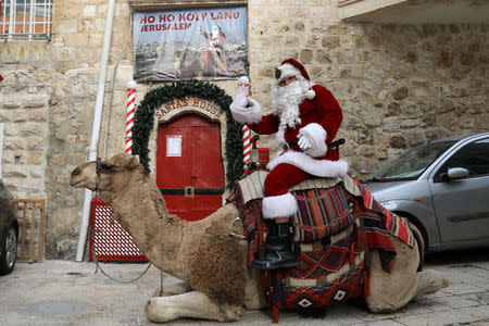 Israeli-Arab Issa Kassissieh, wearing a Santa Claus costume, rides a camel during the annual Christmas tree distribution by the Jerusalem municipality in Jerusalem's Old City December 21, 2017. REUTERS/Ammar Awad