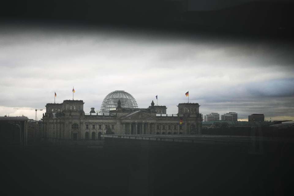 The German parliament Bundestag building, the Reichstag Building photographed through a slit in a blind at the chancellery in Berlin, Germany, Wednesday, Dec. 7, 2022. Officials say thousands of police have carried out a series of raids across much of Germany against suspected far-right extremists who allegedly sought to overthrow the state in an armed coup. Federal prosecutors said some 3,000 officers conducted searches at 130 sites in 11 of Germany's 16 states. (AP Photo/Markus Schreiber)