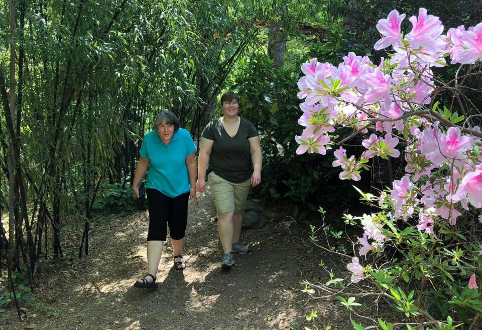 From left to right, Mary Webber and Sarah Schrum both of Prince George stroll through Barb and Gary Rudolph's forest garden path in Petersburg, Va. on April 26, 2022.