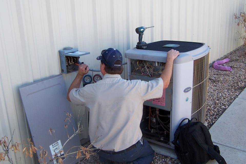 A worker from Integrity Air Conditioning fixes a unit.