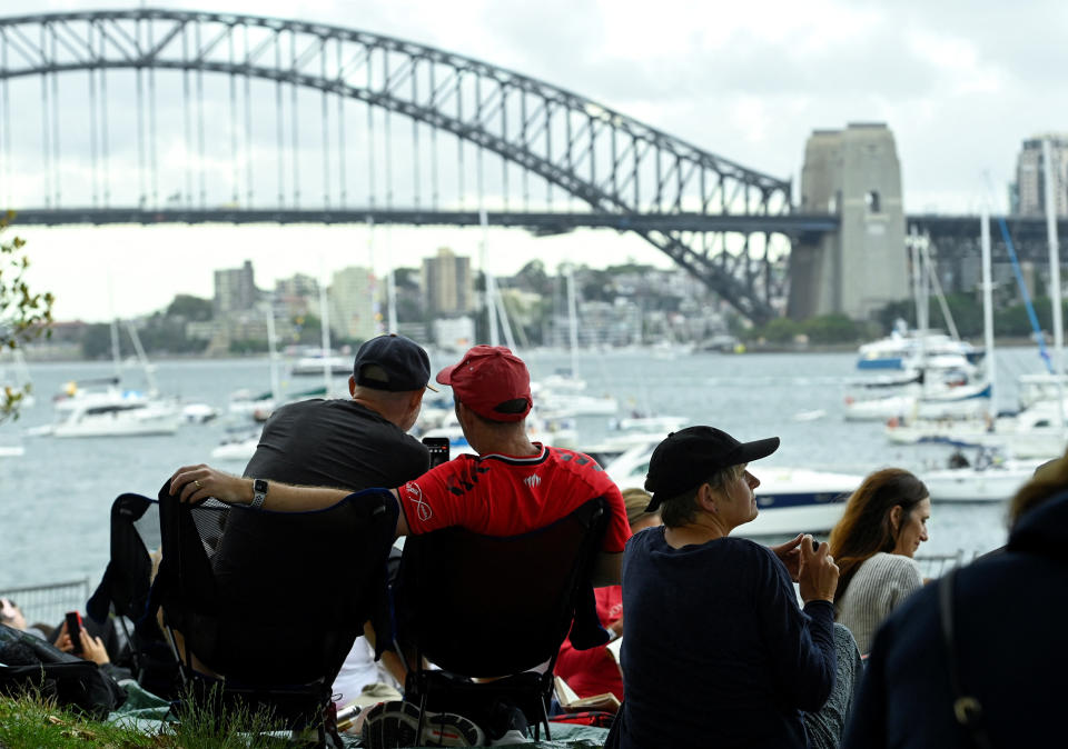 People sit near the Sydney Harbour Bridge ahead of the New Year's Eve celebrations in Sydney, Australia, December 31, 2022. REUTERS/Jaimi Joy