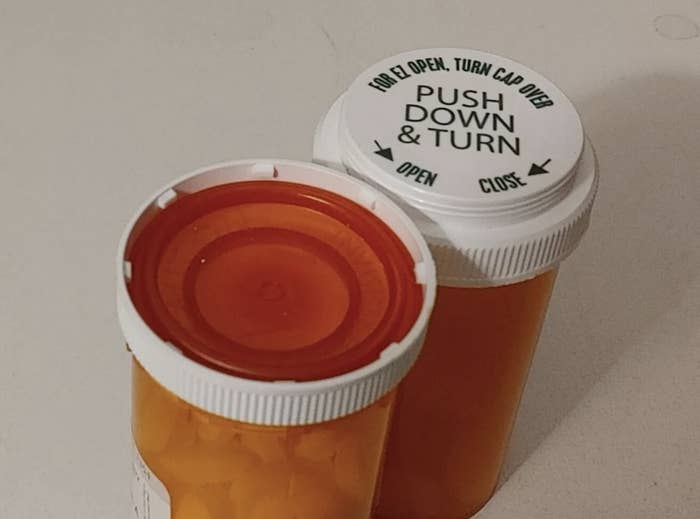 Two orange prescription pill bottles with white safety caps, one showing top text “Push Down & Turn” and directional arrows for opening and closing