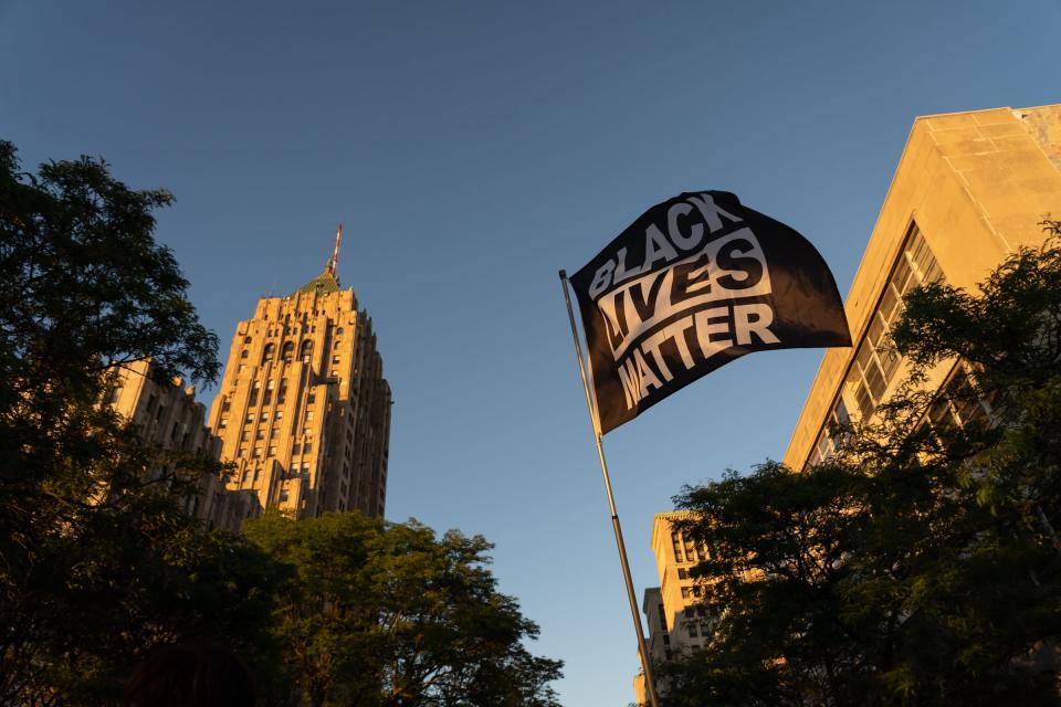 A Black Lives Matter flag waves in the air as protesters with Detroit Will Breathe march along West Grand Boulevard in Detroit on Aug. 18, 2020.