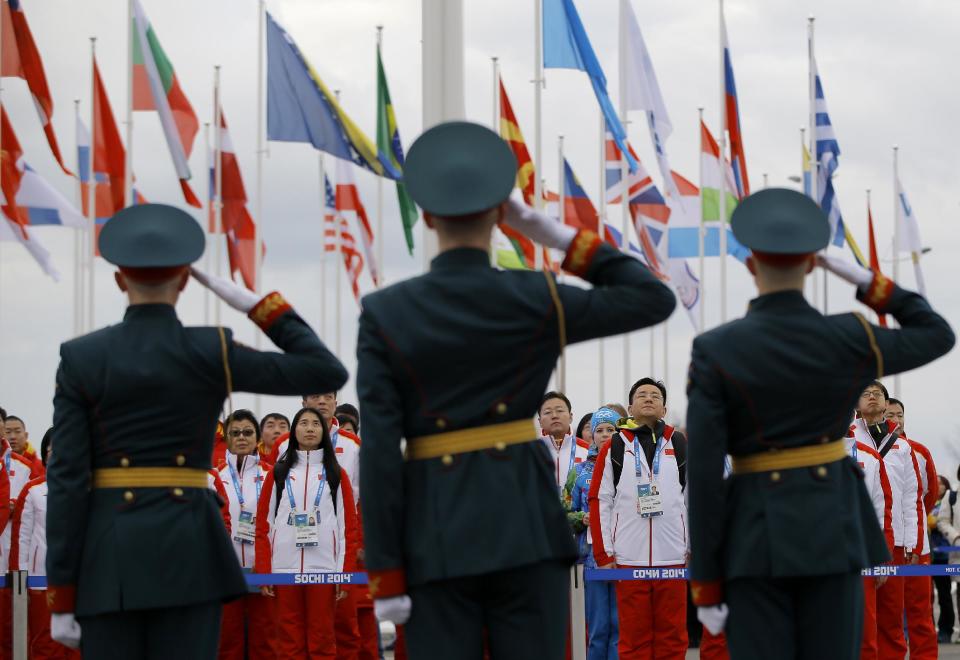 Russian soldiers salute after raising China's flag as the Chinese Olympic team watches during a team welcoming ceremony at the 2014 Winter Olympics, Wednesday, Feb. 5, 2014, in Sochi, Russia. (AP Photo/Vadim Ghirda)