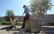 ARLINGTON, VA - JUNE 28: Groundskeeper Lucas Guzman washes the glowing light pool of a bench at the Pentagon Memorial June 28, 2011 in Arlington, Virginia. This year is the 10th anniversary of the September 11 terrorist attacks, in which 184 people were killed at the Pentagon. (Photo by Alex Wong/Getty Images)