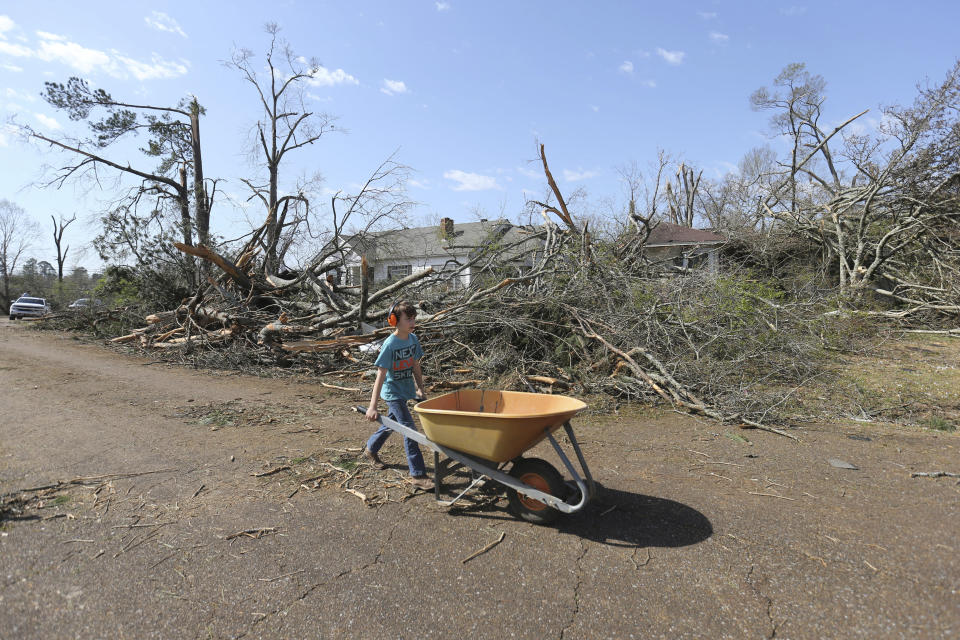 Wyatt Stanford, 10, of Amory, Miss., makes his way to the next house to help removed down trees and other debris, Saturday March 25, 2023. Emergency officials in Mississippi say several people have been killed by tornadoes that tore through the state on Friday night, destroying buildings and knocking out power as severe weather produced hail the size of golf balls moved through several southern states. (Thomas Wells/The Northeast Mississippi Daily Journal via AP)