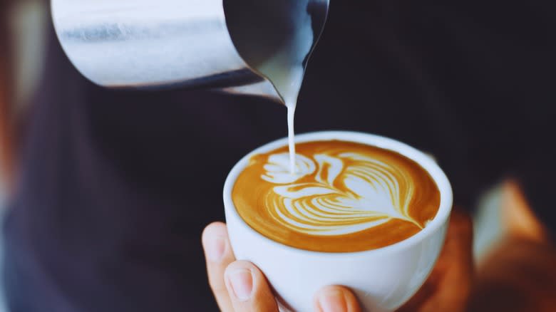 Barista crafting a latte in a white mug