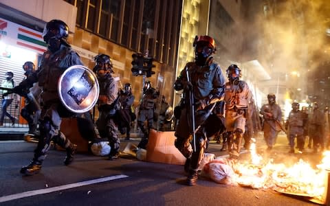 Police passes a burning barricade to break up thousands of anti-government protesters - Credit: THOMAS PETER/REUTERS