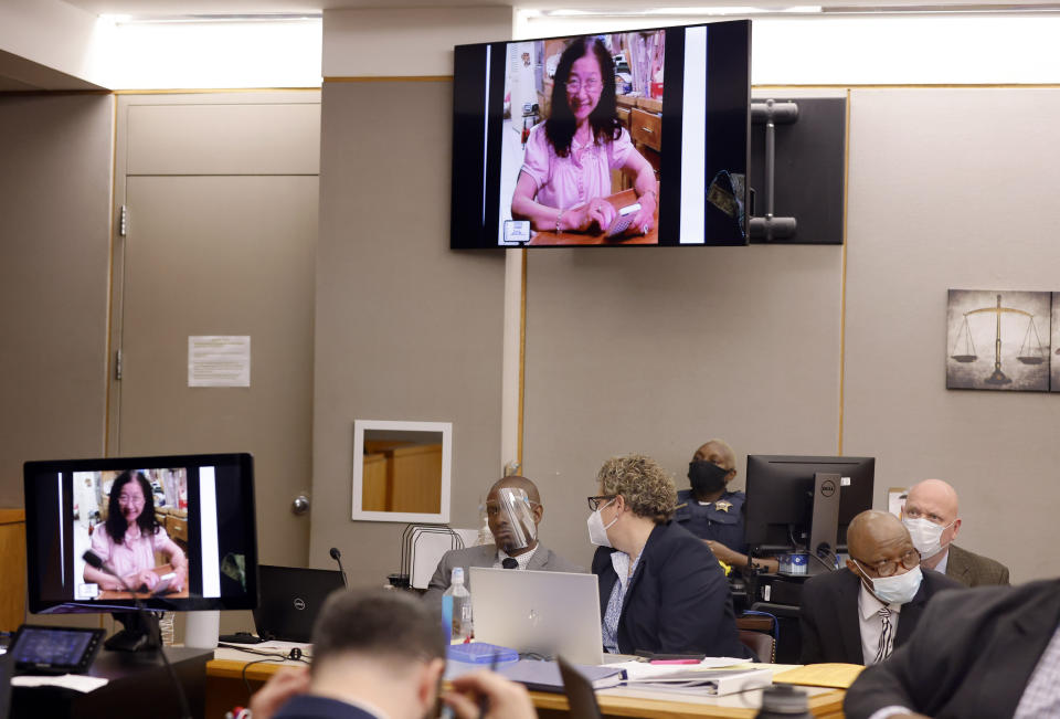 Defense attorney Kobby Warren, left, talks with private investigator Tonia Silva as an image of Lu Thi Harris is shown to the court during the murder trial of Billy Chemirmir, right, at the Frank Crowley Courts Building in Dallas, Tuesday, Nov. 16, 2021. Chemirmir faces life in prison without parole if convicted of capital murder in the death of 81-year-old Lu Thi Harris. (Tom Fox/The Dallas Morning News via AP, Pool)