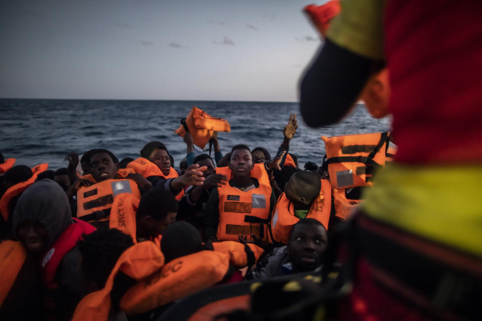 Bamba Bourahima (centro), de 14años y natural de Costa de Marfil, espera para recibir un chaleco salvavidas mientras el rescatista Alberto Agrelo los distribuye entre los migrantes que viajaban en una atestada balsa neumática, tras ser rescatados por el barco de la ONG española Open Arms, en aguas internacionales del Mar Mediterráneo, a 80 millas de la costa de Libia, el 13 de febrero de 2021. En los últimos días, las autoridades libias han impedido ocho intentos de rescate por parte del Open Arms, el barco de la ONG española del mismo nombre, acosando y amenazando a su tripulación. (AP Foto/Bruno Thevenin)