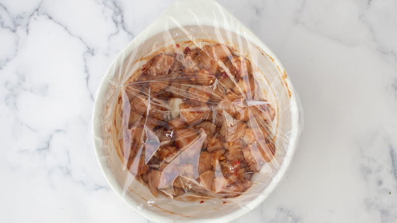 covered bowl of marinating chicken