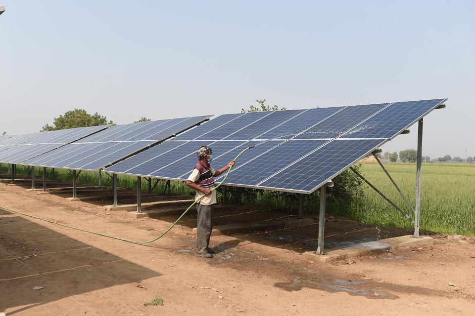 A labourer cleans solar panels installed next to a wheat field at Vahelal village, about 40 km from Ahmedabad on February 3, 2021. (Photo by SAM PANTHAKY / AFP) (Photo by SAM PANTHAKY/AFP via Getty Images)