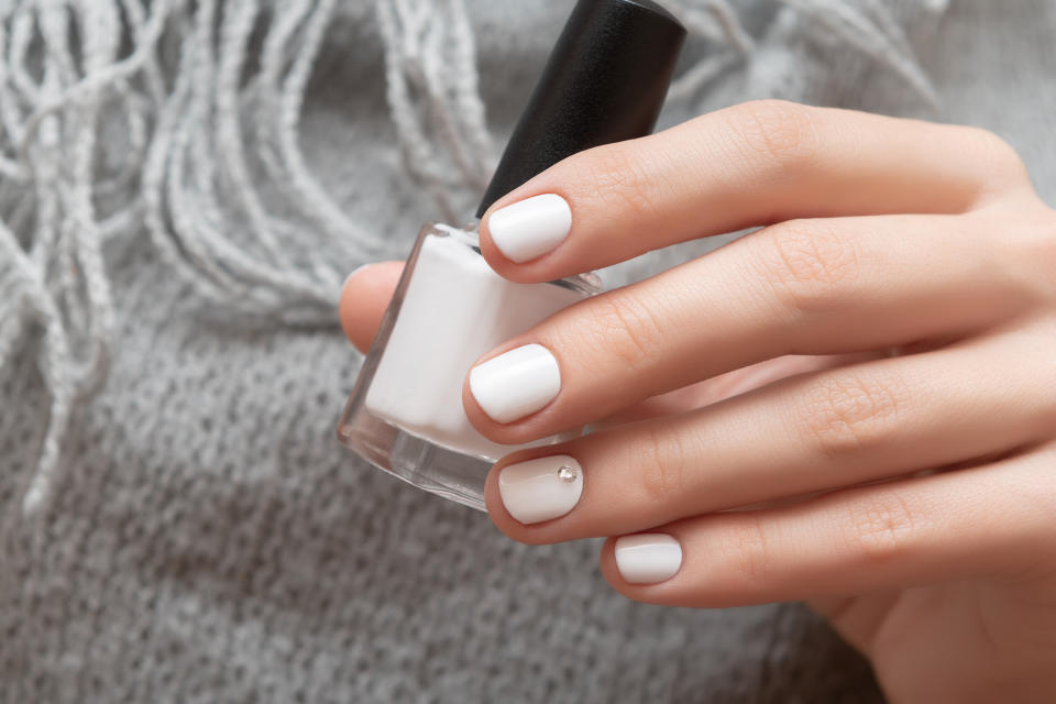 Person holding nail polish with freshly manicured nails suitable for a wedding