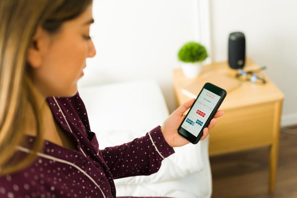 rear view of a woman looking at her menstrual calendar on the smartphone