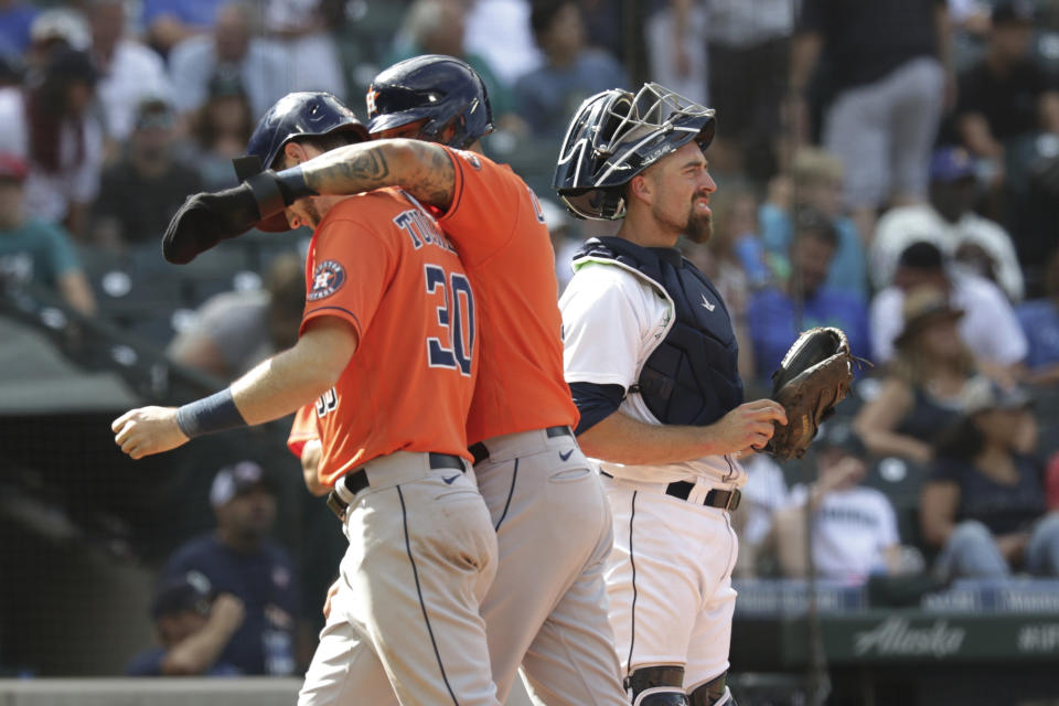 Houston Astros' Carlos Correa welcomes teammate Kyle Tucker (30) at home, next to Seattle Mariners catcher Tom Murphy, following Tucker's two-run home run in the eighth inning of a baseball game Wednesday, July 28, 2021, in Seattle. (AP Photo/Jason Redmond)