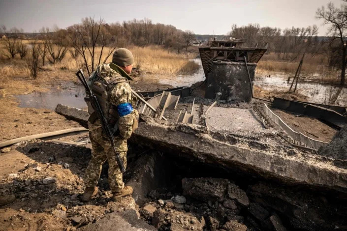 A Ukrainian soldier patrols near a bridge destroyed by the Russian army in the town of Rogan, east of Kharkiv, 30 March 2022 (AFP via Getty Images)