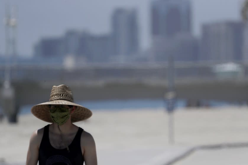 LOS ANGELES, CALIF. - JUNE 11, 2020. A man wadering a protective mask and a wide-brimmed hat on a warm afternoon at Junipero Beach in Long Beach on Thursday, June 11, 2020. A heat wave is expected to give way to cooler temperatures in coming days. (Luis Sinco/Los Angeles Times)