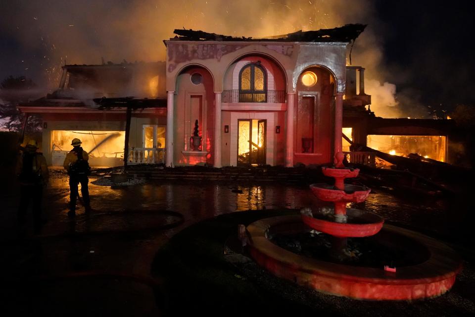 Firefighters work to put out a structure burning during a wildfire Wednesday, May 11, 2022, in Laguna Niguel, California.