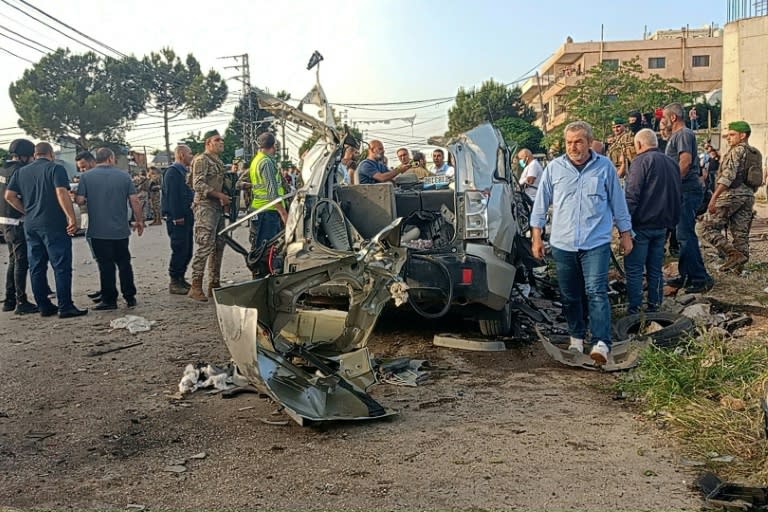 Lebanese soldiers and onlookers gather around the remnants of a car after it was hit by an Israeli strike, reportedly killing a Hamas commander, in Lebanon's Bekaa Valley (Hassan JARRAH)