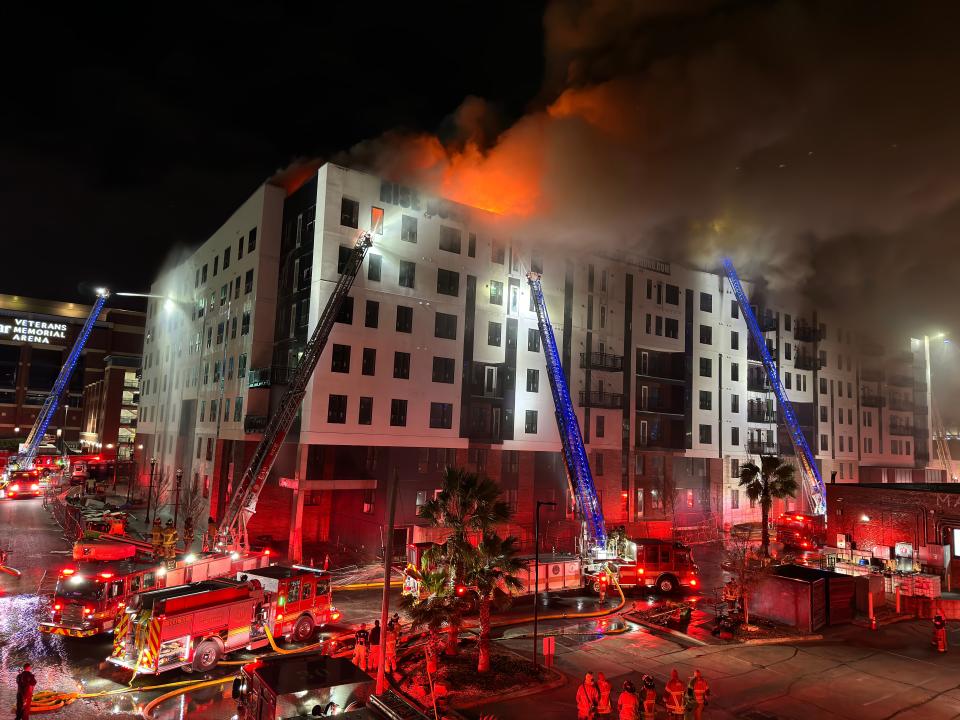 Flames shoot out of the roof of the RISE Doro apartment complex in Jacksonville's stadium district Sunday night as firefighters try to contain the blaze.
