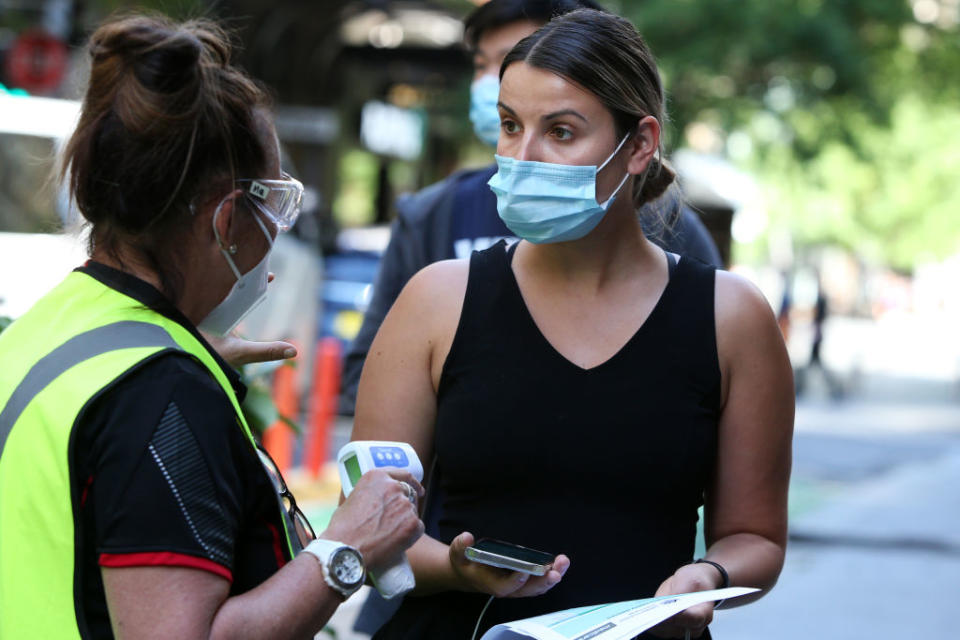 A healthcare worker assists a person as they arrive to check in at the Sonic Healthcare Covid-19 Vaccination hub in the CBD.