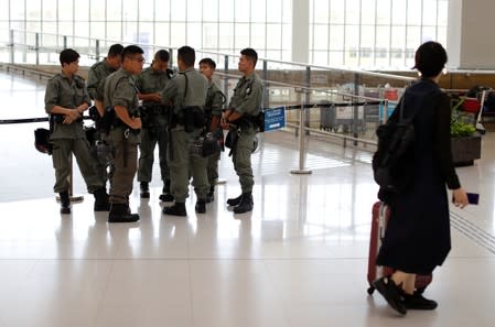 Passenger walks past riot police standing inside Hong Kong International Airport in Hong Kong, China
