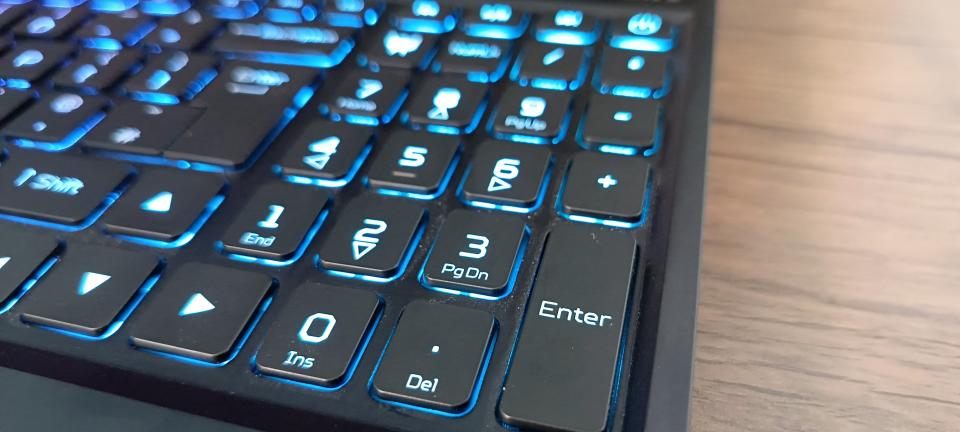 An Abyss Black Acer Predator Helios 16 gaming laptop sitting on a brown wooden desk