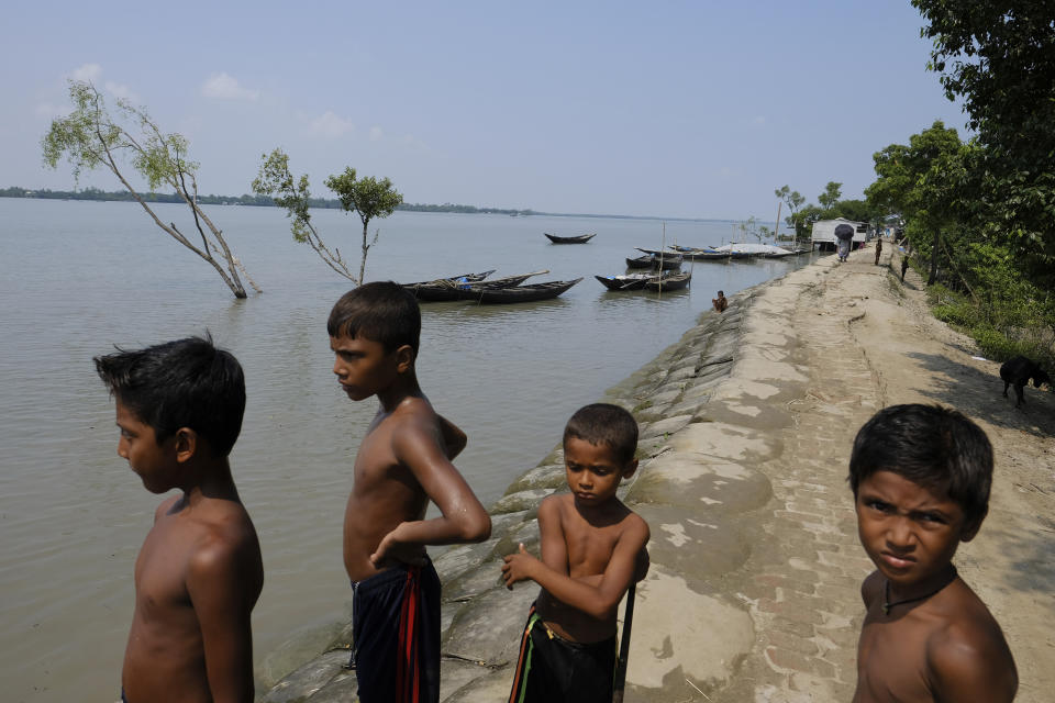 Boys stand by the banks in the coastal village of Gabura, which has been struck by natural disasters several times in Satkhira district, Bangladesh on Oct. 6, 2021. The effects of global warming, particularly increased cyclones, coastal and tidal flooding that bring saltwater further inland, are devastating Bangladesh and destroying the livelihoods of millions, said Mohammad Shamsuddoha, chief executive of the Center for Participatory Research Development, a non-profit. He said that projections show that around 30 million people may be displaced from the country’s coastal regions. “It’s a grave concern for a country like Bangladesh,” he said. (AP Photo/Mahmud Hossain Opu)